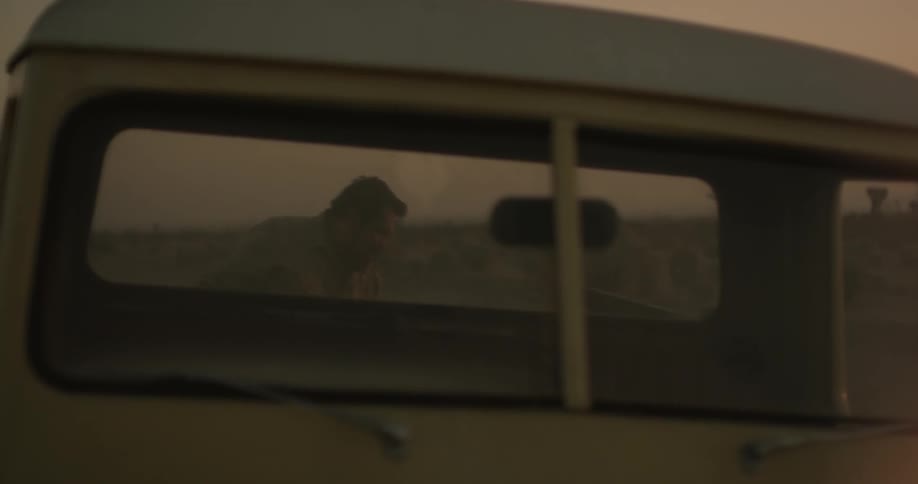 A man removing a box from a pickup bed in the desert