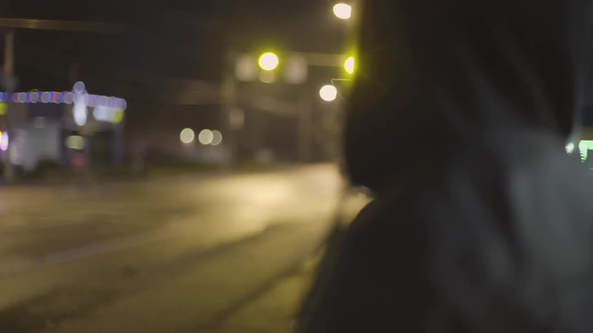 Two men wearing hoods walk together and pass under a chair