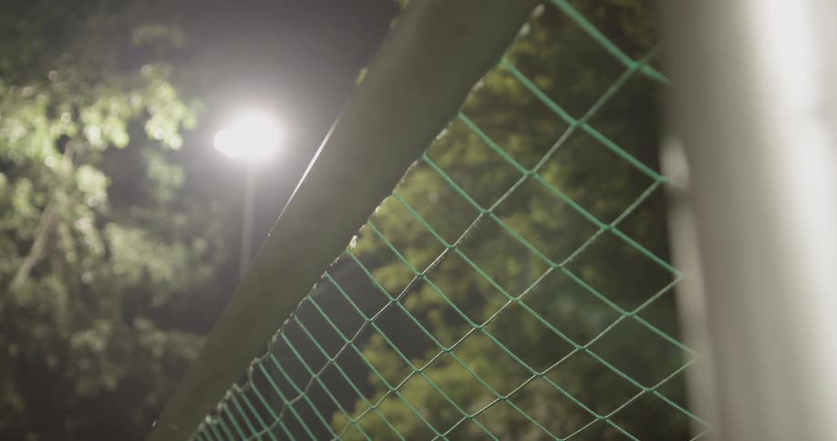 A camera turns around a soccer goal post exposing a bright light at night