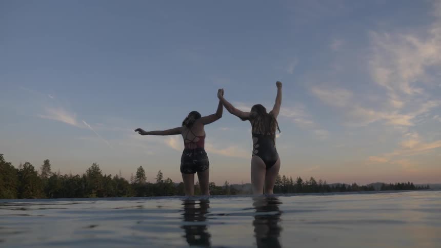 Two women jumping into a lake