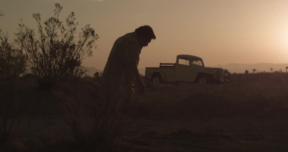 View of a truck in a sunny desert and a man getting up off the ground