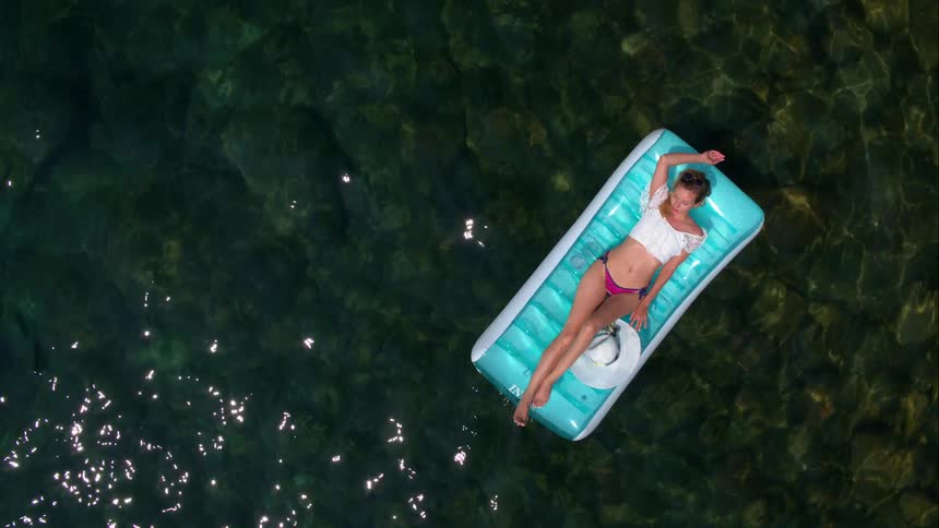 A woman on an inflatable raft floats in a pool