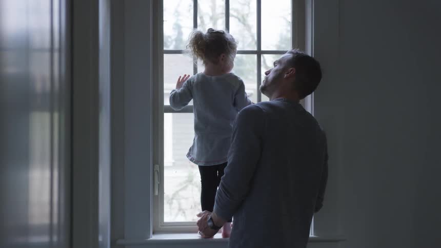 Man watches his daughter looking out the window