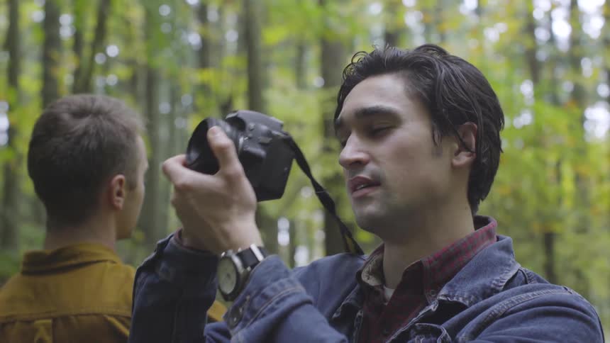 Man aims camera and takes picture in forest