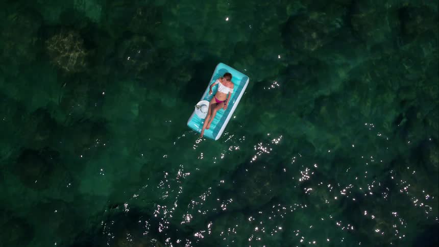 A woman floats on a rafts in clear ocean water
