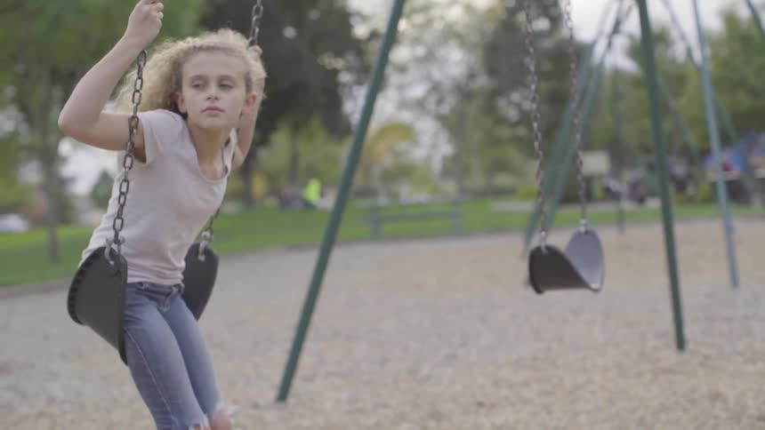 Young girl slowly swings on swings