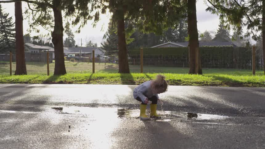 A young girl jumping in a puddle outdoors