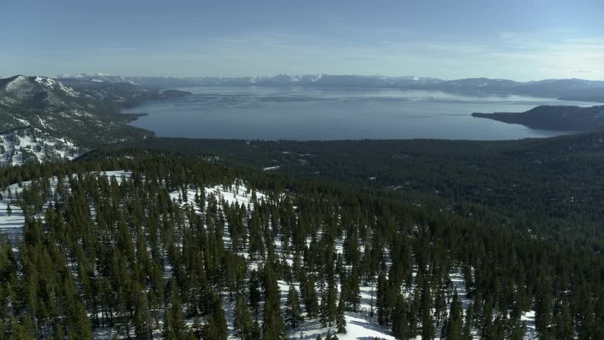 Snow and trees cover hills near a mountain lake