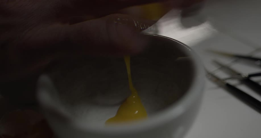 A person putting egg into a bowl