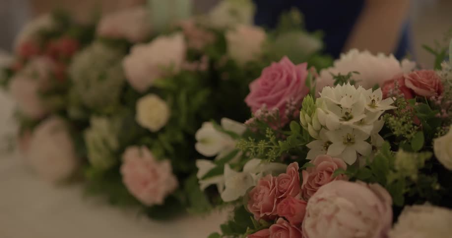 A bouquet of white and pink flowers is set on a table next to a similar bouquet of flowers