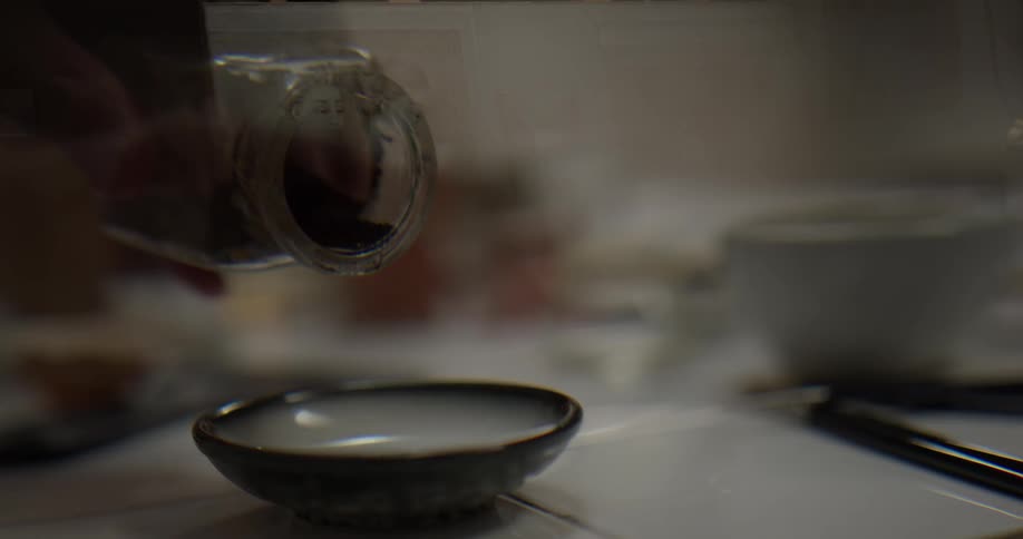 A person pouring seasoning into a bowl