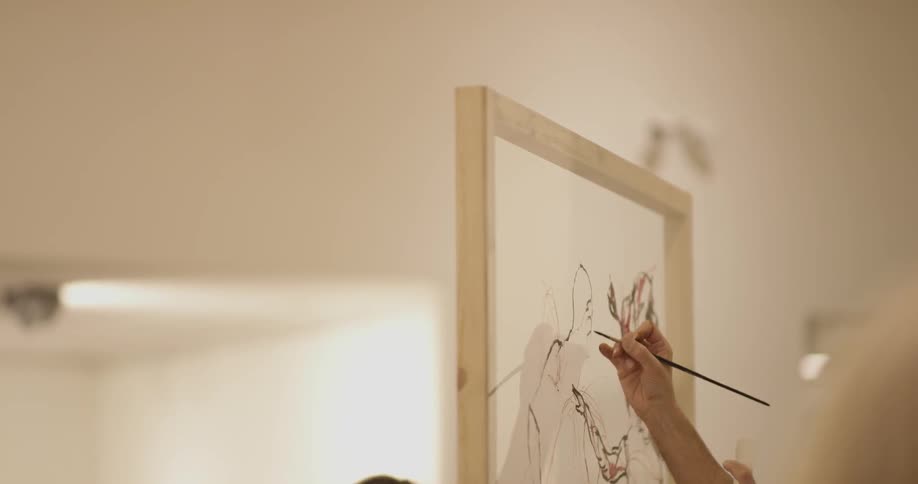 Man outlines shape with brush on canvas