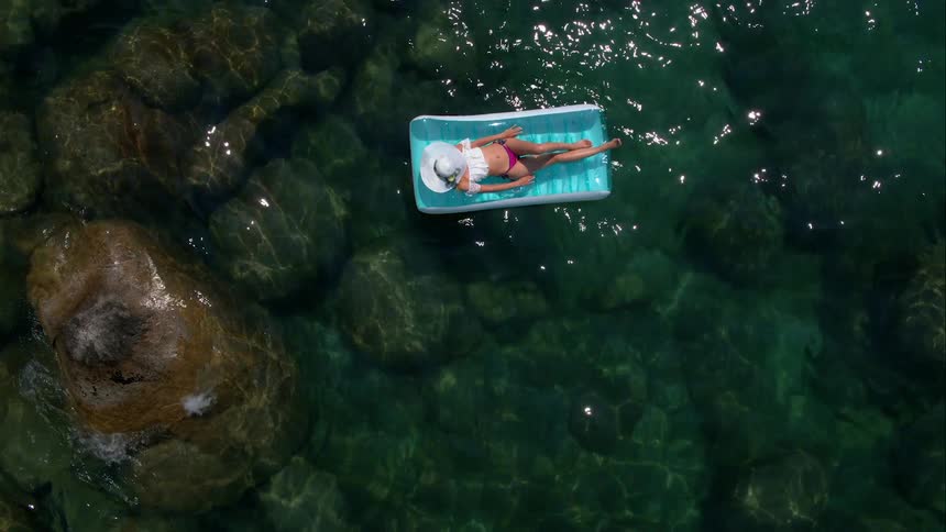 A woman floats on a raft in a clear ocean