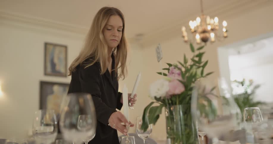 A woman places a candle on a table