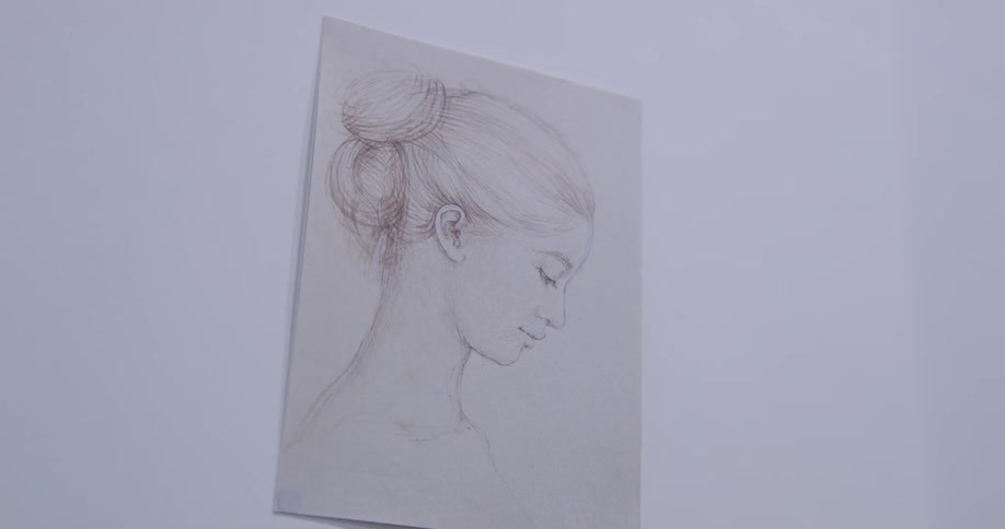 A painting of a woman hangs on the white wall