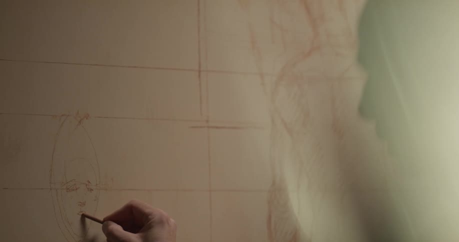 Man sketches on a large piece of paper on the wall