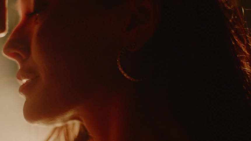 A woman sitting in front of a fire parts her lips