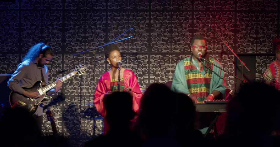 Four people play musical instruments on a stage