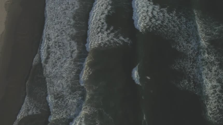 This is a panning overhead aerial view of waves moving towards the shoreline