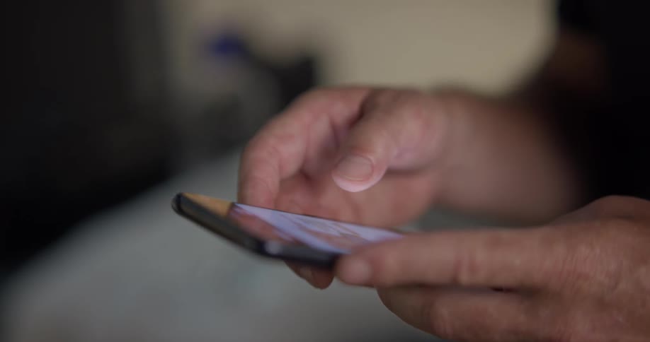 An older man swipes through his phone
