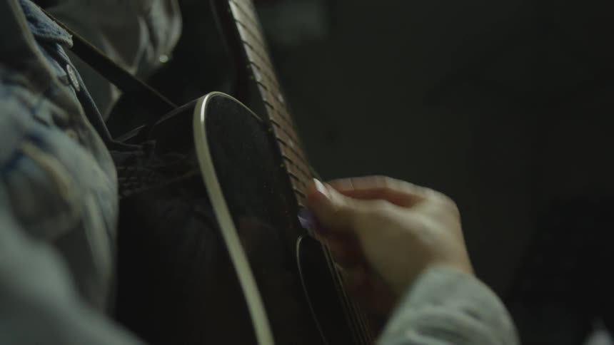 Person strums acoustic guitar