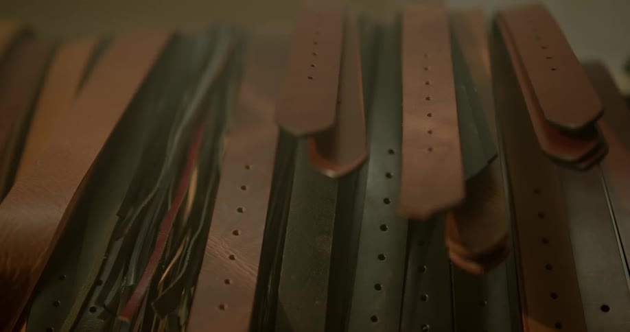 Leather belts hang from a rack