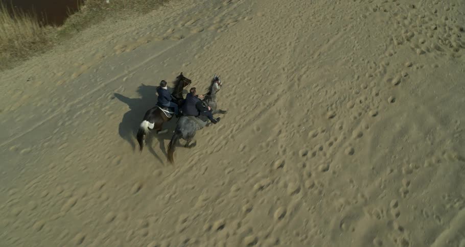 Two people riding horseback in the sand