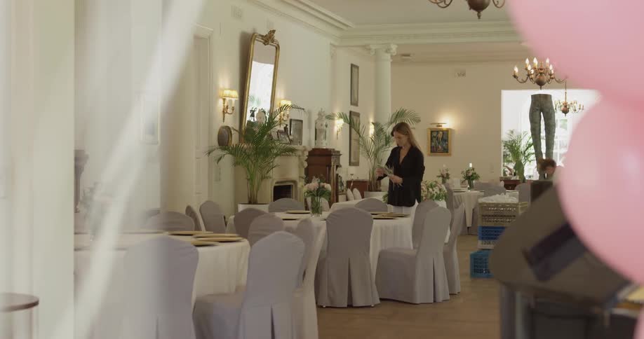 A woman is setting tables in a restaurant