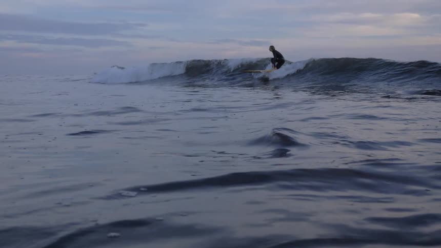 Surfer riding wave in ocean on surfboard