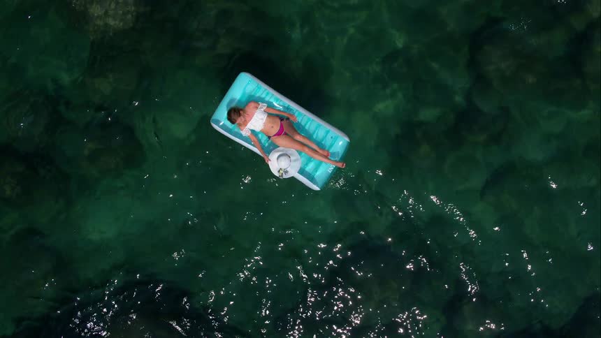 Woman Sunbathing On Raft In Water