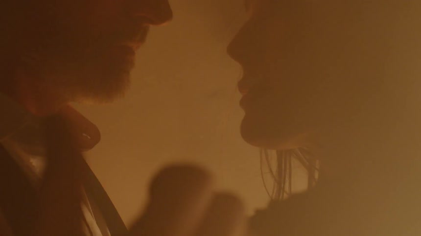 A man and woman kissing next to a fire