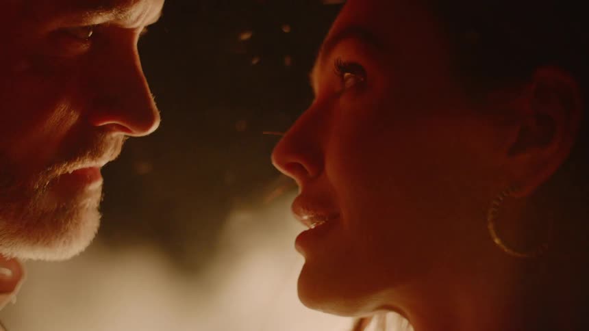 A man and woman talking in front of a fire