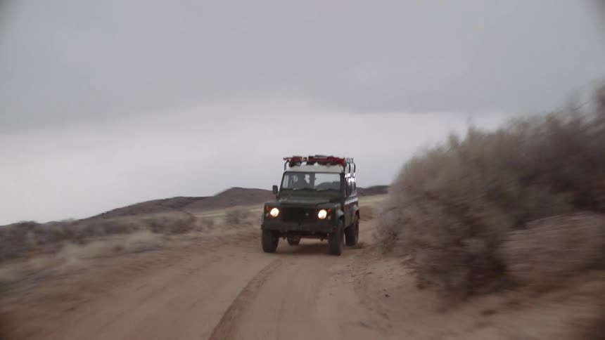 A car is driving on a dirt road