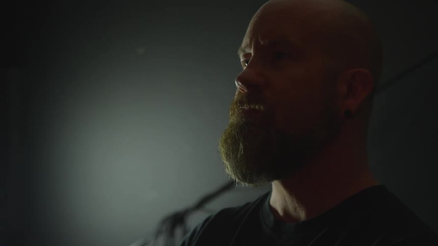 A bearded looks upward in a dim room