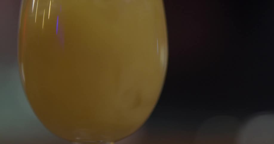 Orange juice is being poured in a wine glass full of ice