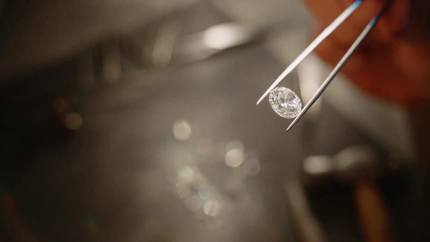 A jeweler holds a diamond with a pair of tweezers
