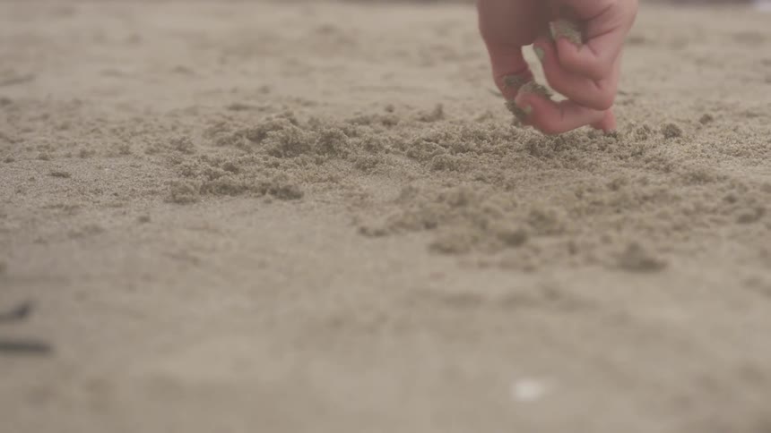 A woman's finger writes in the sand
