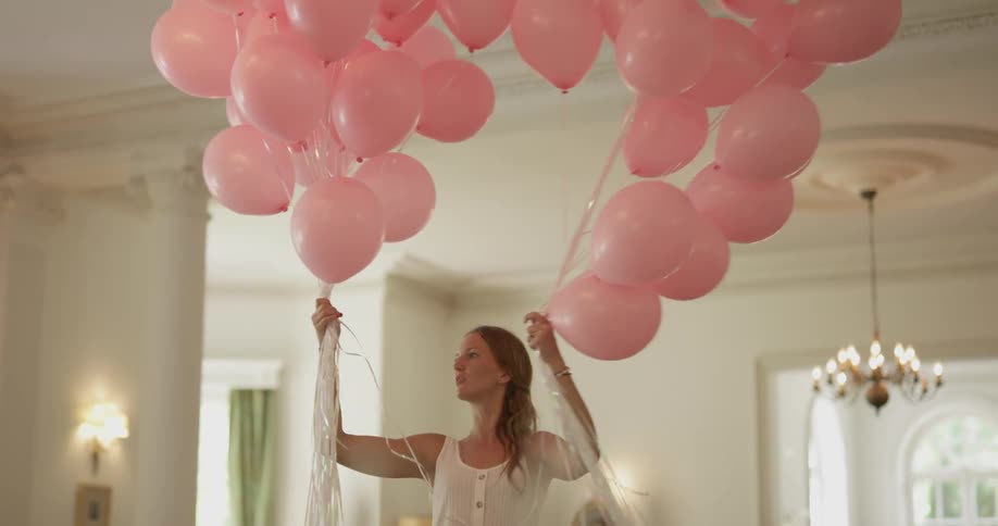 A woman separates a bunch of pink balloons into two separate bunches