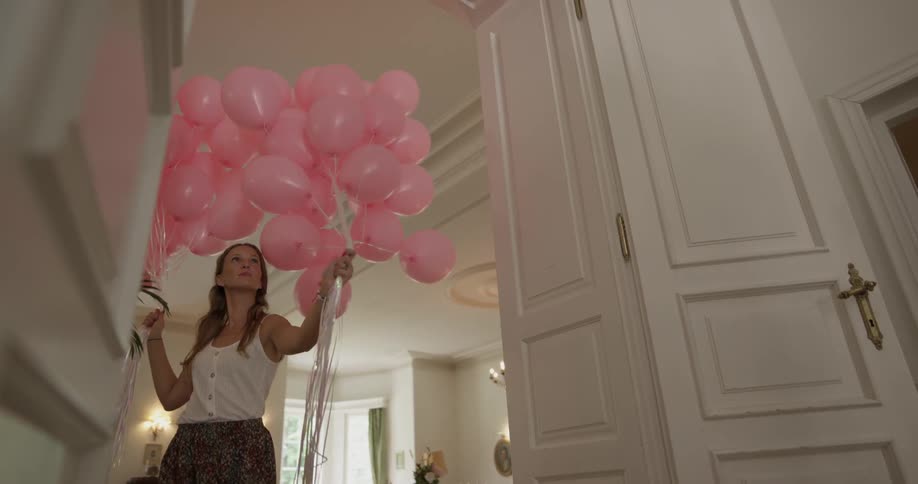 A woman carries a large amount of balloons in both hands