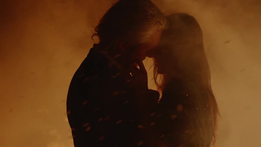 A man and woman are holding each other by a fire