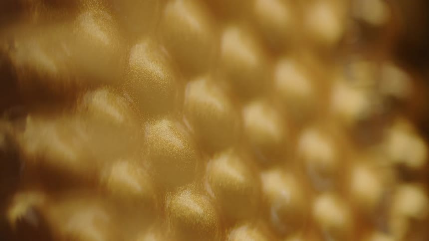 Gold liquid dripping down a honeycomb