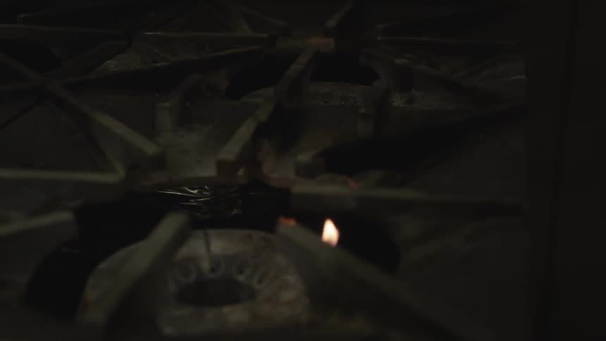 A pilot light burns inside a stove
