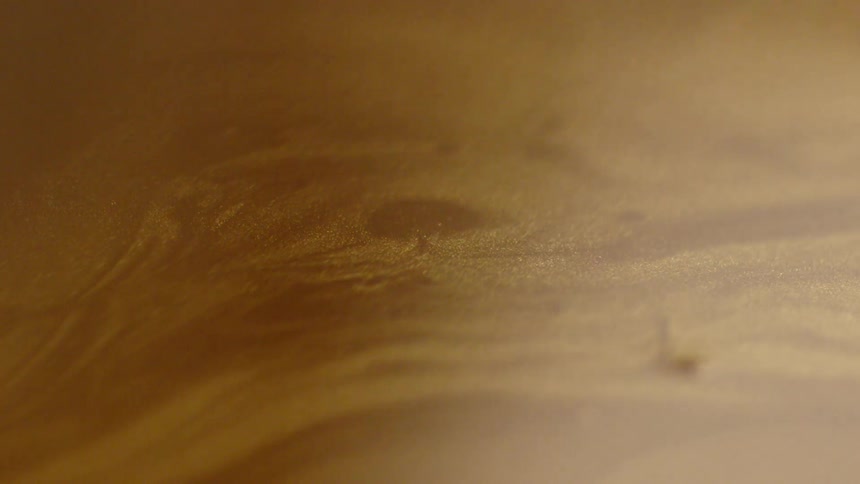 Rippling brown liquid lit up by a light