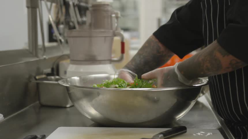 A man mixing salad in a large bowl