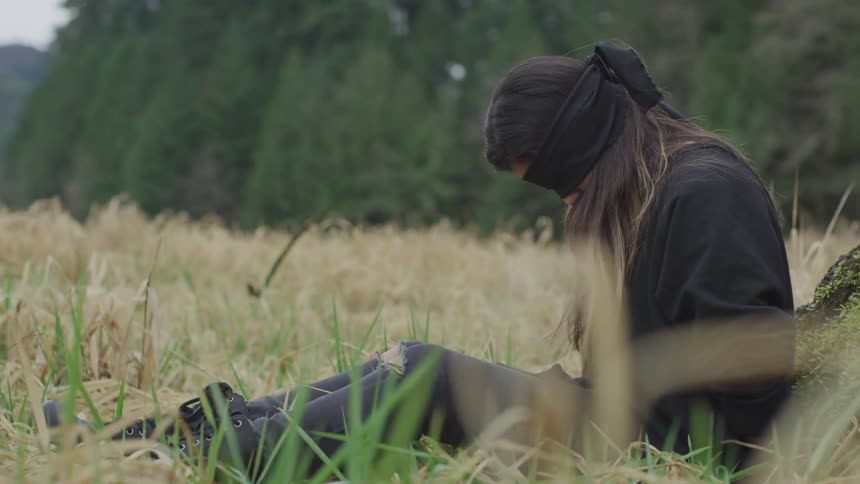 Girl sits in woods blindfolded