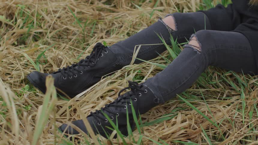 A woman sits on tall grass in a field