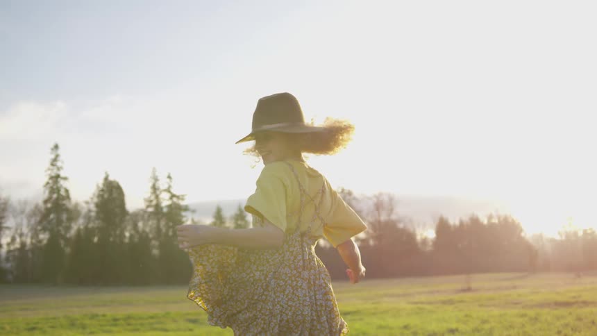 A woman skips on a green field under a bright sun
