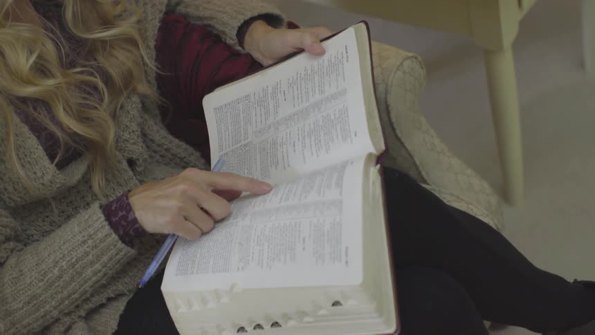 A woman using her finger to guide while reading a book