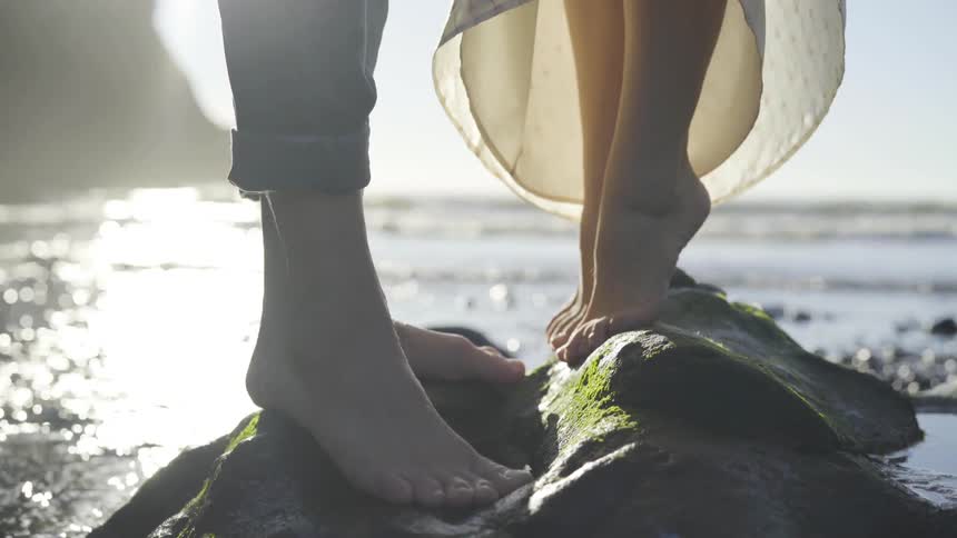 A young girl and her mother standing on rocks in the sea