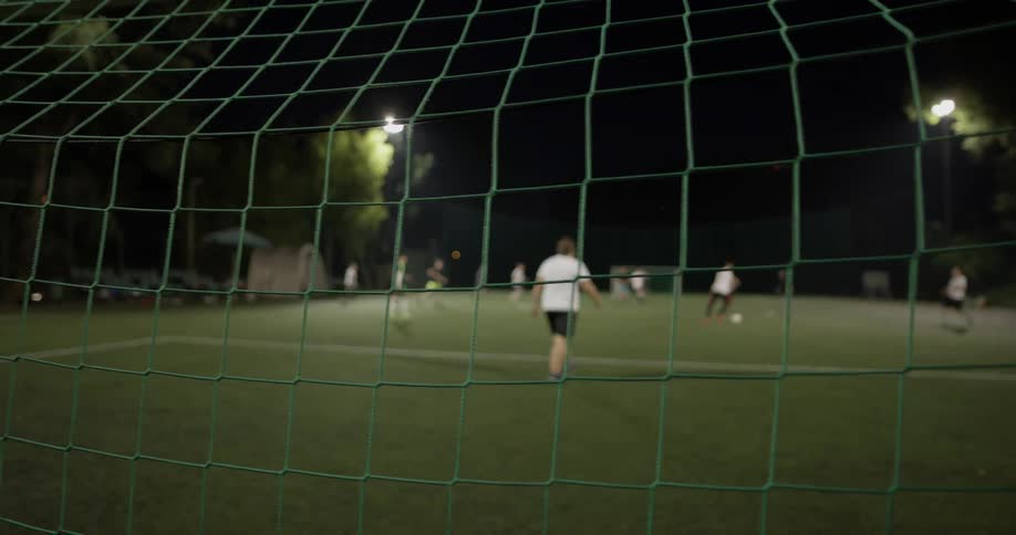 People play soccer on a field at night